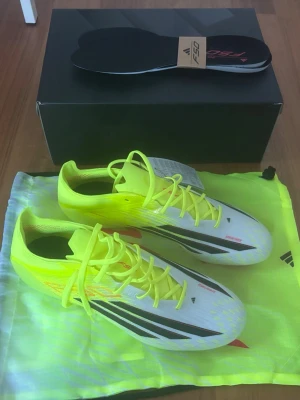 Adidas F50 gula fotbollsskor - Säljer ett par gula Adidas F50 Elite Ag fotbollsskor med svarta och röda detaljer. Perfekta för snabba spelare som vill sticka ut på planen. Storlek 44. Aldrig använda, alla lappar är kvar, kommer med box, skopåse och extra iläggs-sulor. Ursprungspris i affären ligger på 3099kr. Mitt pris: 2200kr men kan diskuteras vid snabb affär. 
