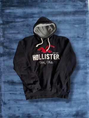 Mörkblå Hollister Hoodie XS-S - Mörkblå Hollister Hoodie i storlek XS-S (Lappen säger L men har krympt en del). Riktigt snygg och trendig hoodie! Inga defekter. Tveka inte på att höra av er⭐️