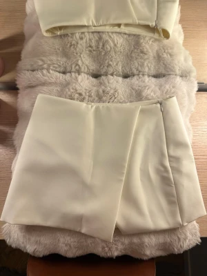 Zara minikjol  - Säljer denna superfina minikjolen från Zara i en krämvit nyans. Inbyggda shorts gör den både snygg och praktisk. Perfekt till både vardag och fest.   Hör av dig vid frågor!🤍 