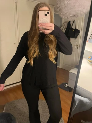Svart stickad tröja i basic modell - En enkel och stilren svart stickad tröja med rund hals och långa ärmar. Tröjan har en rak passform och ribbstickade muddar vid ärmslut och nederkant. Perfekt basplagg för alla tillfällen. Lite tunnare stickad, lite nopprig på vissa ställen