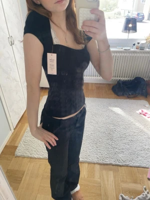 Svart tight topp med kort ärm - Säljer en svart, tight topp med korta ärmar och söt, något hjärtformad urringning. Toppen har en figurnära passform och är perfekt att styla med jeans eller kjol. Materialet känns mjukt och stretchigt, vilket gör den bekväm att bära hela dagen. Aldrig använd🤗