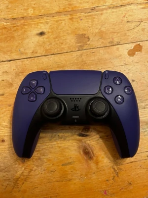 Lila PS5 handkontroll - Säljer en lila Sony DualSense handkontroll till PlayStation 5. Kontrollern har en snygg matt finish, klassisk ergonomisk form och tydliga knappar. Aldig använd efter som kontrollen var till fel konsol. Perfekt för gaming på PS5.
