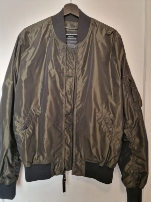 Olivgrön bomberjacka Alpha Industries - Snygg olivgrön bomberjacka från Alpha Industries med klassisk passform. Supersnygg till sommaren och knappt använd/som ny 
