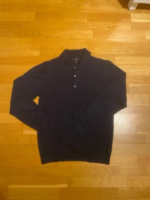 Mörkblå tröja med polokrage från Matinique - Snygg mörkblå tröja från Matinique med klassisk krage och knäppning framtill. Tröjan har långa ärmar och är i Storlek M, använd max 2-3 gånger. 