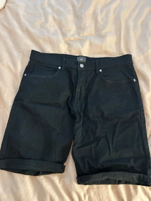 Svarta slim fit shorts från H&M - Svarta shorts från H&M i slim fit-modell. Klassisk femficksdesign med knapp och dragkedja framtill. Shortsen har uppvikta benslut och är tillverkade i ett mjukt bomullsmaterial. Perfekta för en stilren och enkel look.