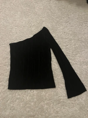 Svart one shoulder topp Gina Tricot - Säljer en svart one shoulder topp från Gina Tricot. Materialet har en lätt glansig struktur💗 använd två gånger