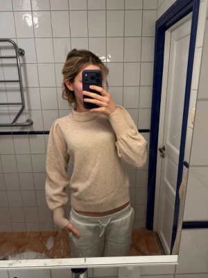 Beige stickad tröja Selected Femme - Mysig beige stickad tröja från Selected Femme med rund halsringning och ribbade muddar vid ärmslut och nederkant. Tröjan har en enkel och stilren design, perfekt för lager på lager och passar till det mesta.