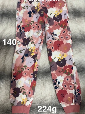 Blommiga mjukisbyxor med rosa toner - Säljer ett par mjukisbyxor med färgglatt blommönster i rosa, rött, lila och vitt. Byxorna har resår i midjan och vid bensluten för skön passform. Perfekta för chill dagar eller när du vill ha något bekvämt och snyggt.🌸 sparsamt använda. En mindre knappt synligt fläck på benet. Storlek 140 