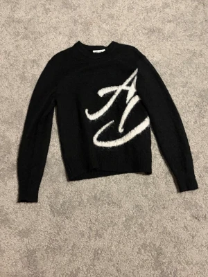 Ame dore limited edition mohair sweater  - Säljer en svart stickad tröja med en stor vit bokstav i grafisk stil på framsidan. Använd fåtal gånger. Storlek XS men sitter som S 