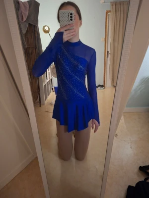 Djupblå konståkningsklänning med kristaller - Säljer denna superfina konståkningsklänningen med kristaller! Den är från märket iEFiEL köpt från Joom för 220kr. Strl S. Har använt 2 gånger så den är nästan ny. Absolut en favorit, men säljer pga jag har nytt program med rosa tema. 