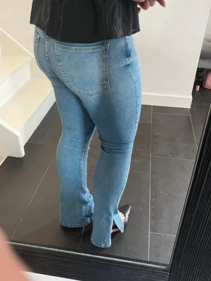 Ljusblå jeans med slits nertill - Säljer ett par ljusblå jeans bootcut med slits nertill på benen. Jeansen har klassiska bakfickor och är tillverkade i stretchigt denimtyg som sitter snyggt. De är från Gina tricot i storlek M💕