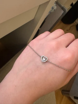 Silverarmband med hjärta och stenar - Snyggt och stilrent armband i silverfärg med ett hjärtformat hänge dekorerat med gnistrande stenar. Är i äkta silver.