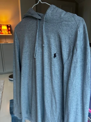 Grå hoodie Polo Ralph Lauren - Snygg grå hoodie från Polo Ralph Lauren med klassisk huva och dragsko. Tillverkad i mjukt material och har den ikoniska svarta loggan broderad på bröstet. Perfekt för en chill och stilren look. Passar dig som är mellan 170-180. Tveka inte på att fråga vid minsta lilla fundering😊 skickas inom 1 dag‼️