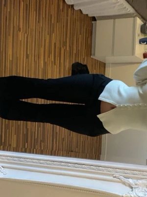 Svarta utsvängda kostymbyxor - Säljer ett par svarta kostymbyxor med utsvängda ben och låg midja. Byxorna har en klassisk look och är perfekta till en snygg outfit. Modellen är i petite 