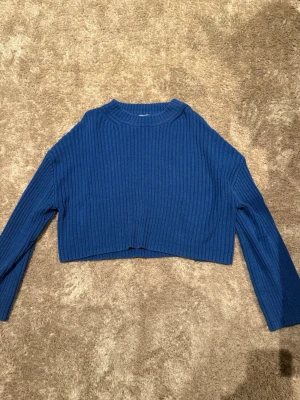 Blå cropped stickad tröja H&M - Säljer en blå cropped stickad tröja från H&M. Tröjan har ribbad struktur, långa ärmar och rund halsringning. Perfekt för lager på lager och enkel att styla till olika outfits. Passar även för dem som har storlek S. Skriv för bilder om ni vill veta hur den sitter på. 