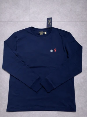 Ralph lauren tröja - En helt ny ralph lauren långärmad med färgen blå som passar perfekt vid alla tillfällen, med den röda loggan. PRIS KAN DISKUTERAS!!