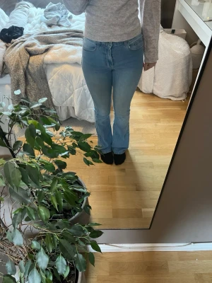 Ljusblå bootcut jeans - Säljer ett par ljusblå bootcut jeans med klassisk femficksdesign och normal midja. Jeansen har en lätt utsvängd passform nertill och är perfekta för en avslappnad och trendig look. Materialet är denim i bomull med lite stretch för extra komfort.