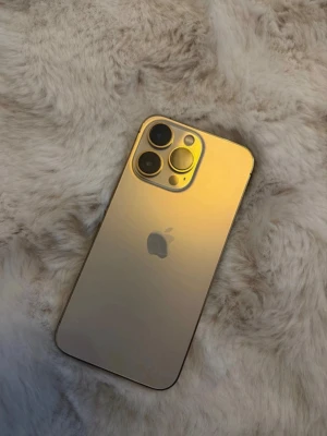 Guldfärgad iPhone 13 Pro  - Superfin iPhone 13 Pro i guldfärg med stilren design och trippelkamera på baksidan. Telefonen har inga repor eller skador. Batterihälsan ligger runt 74% om jag minns rätt. Telefonen fungerar fint utan problem. Laddare medföljer ej då den gick sönder 
