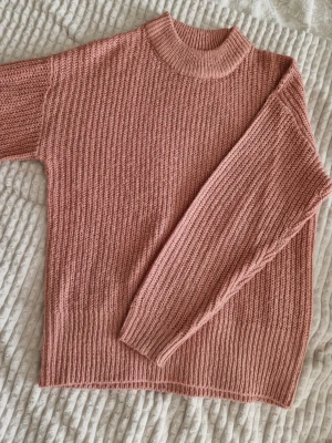 Rosa stickad tröja med ribbad struktur - Mysig rosa stickad tröja med ribbad struktur och hög hals. Tröjan har långa ärmar och breda muddar vid ärmslut och nederkant. Skulle säga oversize😍 tror jag köpt den från Boohoo