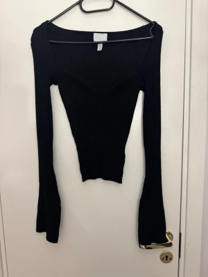 Svart ribbad långärmad topp - Snygg svart ribbad topp med lång ärm och v-ringad hals. Modellen är figurnära. Materialet är stretchigt och bekvämt, vilket gör den enkel att bära hela dagen.