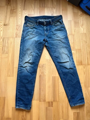 Vintage jeans från diesel - Snygga blå tapered fit jeans från diesel med klassisk femficksdesign och slitningar på framsidan. Perfekta för en avslappnad och trendig look. Storlek 31, passar w32-34. Pris går att diskutera