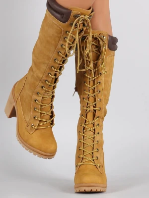 Gula snörade höga stövlar med klack - Säljer ett par höga stövlar i senapsgult med grov snörning framtill och kraftig klack. Stövlarna har vadderad brun kant upptill och är tillverkade i mockaimitation. Perfekta för dig som vill sticka ut med en cool och trendig look. Obs märke/rispa framtill, se bild. Annars fint skick