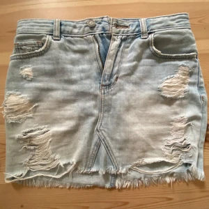Ljusblå jeanskjol från Hollister - Ljusblå jeanskjol från Hollister med slitna detaljer. Säljer på grund av att den är för liten och inte kommer till användning!! Hör av dig vid frågor🤗pris kan diskuteras. 36-37 cm i midjan.