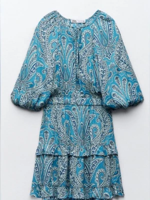 Blå paisleymönstrad klänning Zara - Zaraklänning som inte går att få tag på längre!! Superfin blå kort klänning från Zara med paisleymönster och volangdetaljer. Klänningen har puffiga trekvartsärmar och rund halsringning. Perfekt för dig som gillar färg och mönster!