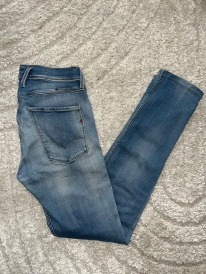 Replay Anbass jeans  - Ljusblåa Replay Anbass jeans som har ett mjukt matrial. Midja 38cm, längd 105cm. Obs bak på jeansen är tyget något förtunnat - se närbild. Jag har tyvärr ingen bild på när jag bär jeansen på. För bättre inblick i passformen rekommenderar jag att googla på modellnamnet. För storleksguide kolla måtten noggrant då jeansen alltid kan vara uppsydda heller krympta och jag ej tar emot returer :) 1,90