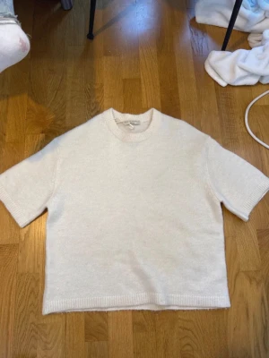 Vit stickad t-shirt med kort ärm - Säljer en enkel och stilren vit stickad t-shirt med korta ärmar och rund hals. 