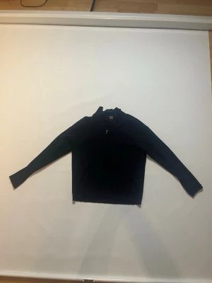 Mörkblå långärmad tröja med dragkedja storlek 158-164 från Lindex - En stilren mörkblå långärmad tröja med halv dragkedja vid halsen. Tröjan har en hög krage och är tillverkad i ett mjukt material som passar perfekt för kyligare dagar. Enkel och klassisk design som funkar till många olika outfits. Storlek 158-164 tröjan är från Lindex