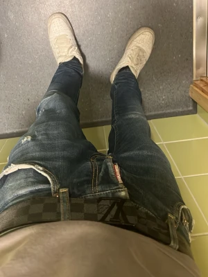 Mörkblå slim fit jeans från Dsquared2 - Säljer ett par mörkblå slim fit jeans från Dsquared2 med slitningar och detaljerade tvättade partier. Jeansen har klassisk femficksmodell och synlig logotyp vid gylfen. Perfekta för en trendig och avslappnad stil.