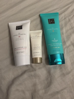 Rituals hudvårdsprodukter 3-pack - Säljer ett set med tre Rituals hudvårdsprodukter: en vit body cream med körsbärsblom, en liten ansiktsmask i beige tub och en turkos handkräm. Alla tuber har snygg design och är perfekta för dig som gillar lyxig hudvård.