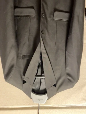 Kavaj only sons med brallor - Stilren svart kavaj från Matinique med klassisk passform och två knappar framtill. Kavajen har två fickor med lock och en innerficka, perfekt för en dressad look. Materialet känns mjukt och har en lätt glansig finish. För en hundring extra kan du få me matchande brallor.