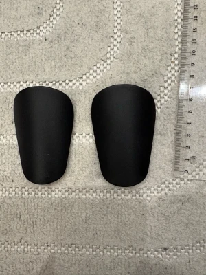 Super små fotbollsbenskydd  - Super små fotbollsbenskydd, känns knappt på benen, inga skador på de, fungerar jätte bra och jätte bekväma att spela med.                                       Jag la en linjal bredvid i första bilden så att det syns hur små de verkligen är. 