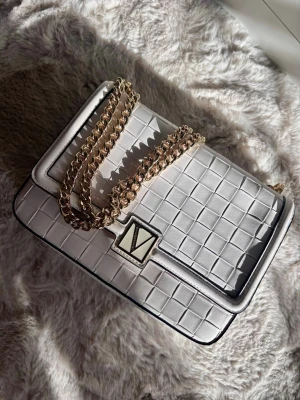 Vit Victorias’s Seacret väska - Jättesnygg Vit väska med gulddetaljer ifrån Victoria’s Seacret (2021/22 modellen), som tyvärr inte blivit använd därav säljer! Insidan är ljuslila med de klassiska VS mönstret och dessutom har kedjan två olika längder att justera till..Bara att höra av sig om mer bilder eller andra funderingar få svarar jag gärna!☺️💞