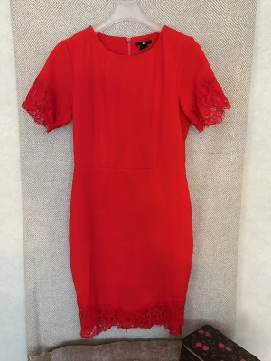 Röd spetsklänning från H&M - Snygg röd klänning från H&M med spetsdetaljer på ärmar och nederkant. Klänningen har korta ärmar och en figurnära passform som markerar midjan. Perfekt för dig som vill sticka ut med en färgstark look. Nypris 799kr