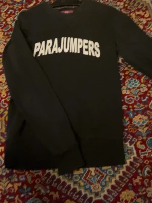 Svart fleece tröja Parajumpers - Svart fleece tröja från Parajumpers med stor vit logga över bröstet. Klassisk rund halsringning och långa ärmar. Perfekt för dig som gillar enkel och stilren design med fokus på komfort. Denna tröja kan jag garantera äktheten på, eftersom jag köpte den på nk för ett par år sedan! Storleken är S och passar prima på S!