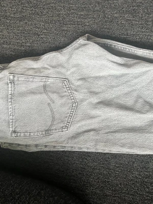 Ljusgrå jack&jones jeans - Säljer ett par ljusgrå jeans med rak passform och klassisk femficksdesign. De har en liten defekt på vänster knät men det syns knappas. 