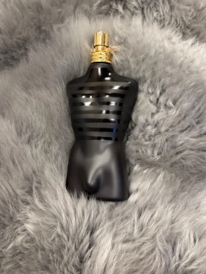 Oanvänd - Le Male Le Parfum från Jean Paul Gaultier - En ikonisk parfymflaska formad som en manlig torso i svart och guld från Jean Paul Gaultier. Flaskan har mattsvart finish med blanka svarta ränder och ett guldfärgat sprayhuvud. Perfekt för dig som gillar unika och snygga parfymflaskor.