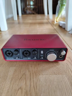 Focusrite Scarlett 2i2 ljudkort - Säljer ett rött Focusrite Scarlett 2i2 externt ljudkort i metall med två XLR/tele-ingångar, stora volymrattar och hörlursutgång. Perfekt för inspelning och musikproduktion, kompakt och stilren design. Modellbeteckning och certifieringar syns undertill.  Finns två repor på den men inget som syns om man inte vet om det.  Testat idag, 5/6, och den fungerade som den ska!