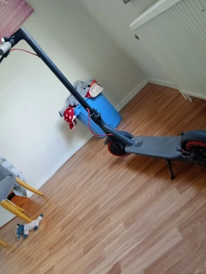 Xiaomi Mi Electric 25km/h - Säljer en svart elsparkcykel med röda detaljer på däcken och bromskabeln. Stilren design med bred fotplatta och stödben. Perfekt för att ta sig runt snabbt och smidigt i stan eller till skolan. Kommer utan laddare. En Xiaomi som går i 25km/h. Hämtas helst på plats. 