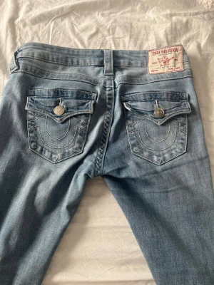 Ljusblå lowrise True Religion jeans  - Säljer ett par ljusblå jeans från True Religion som är väldigt lowrise. Tror dom är i strl 25 (32 i europeisk mått) det motsvarar en xs det är ellerfall vad jag är och dom sitter perfekt. Tyvärr avklippta där nere vid bena så dom passar mig bättre som är 167