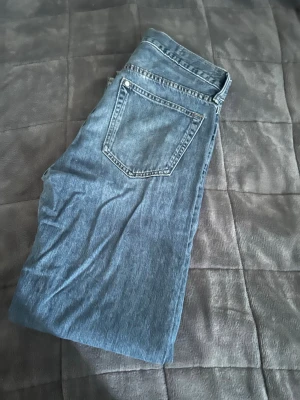 Blå raka jeans i klassisk modell - Säljer ett par blå jeans i klassisk rak modell med fem fickor och normal midja. Jeansen har en tidlös tvätt och silverfärgade detaljer vid knappar och nitar. Perfekta till vardagslooken och passar till det mesta.