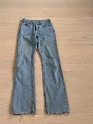 Ljusblå raka jeans från Bikbok  - Säljer ett par klassiska ljusblå raka jeans från Levi's med hög midja och fem fickor. Jeansen har råa, fransiga benslut och tidlös tvätt. Perfekta för en avslappnad och trendig look.
