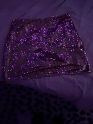 Glittrig rosa minikjol - Säljer en superglittrig rosa minikjol med paljetter. Kjolen har en tight passform och är perfekt för dig som vill sticka ut. Materialet känns mjukt och stretchigt, vilket gör den bekväm att bära hela kvällen. 