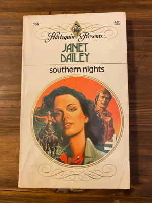 Southern Nights av Janet Dailey - En romantisk pocketbok på engelska, 'Southern Nights' av Janet Dailey. Omslaget har en färgglad illustration med western-tema och motiv av hästar och personer. Boken har vit framsida med dekorativa detaljer och klassisk Harlequin-design.