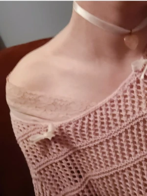 Rosa virkad off-shoulder tröja med rosetter  - Söt rosa stickad tröja i virkad stil med off-shoulder passform och dekorativ rosett på axeln som jag lagt till själv. Tröjan och Materialet känns mjukt och lätt.