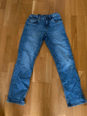 Blåa jeans - Säljer ett par klassiska blå jeans med rak passform i storlek 164. Är snygga och passar till alla olika typer av tillfällen. Tveka inte på att höra av dig vid funderingar!