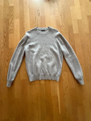 Ljusgrå stickad tröja Massimo Dutti - Ljusgrå stickad tröja från Massimo Dutti i mjukt material. Tröjan har rund halsringning, ribbade muddar vid ärmslut och nederkant samt en enkel, stilren design. Perfekt för dig som gillar minimalistisk och klassisk stil.